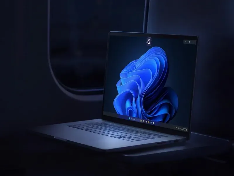 A MacBook on a train showing the Windows desktop of a Shadow PC