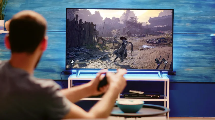 A player on the sofa plays Phantom Blade Zero on a TV with a controller