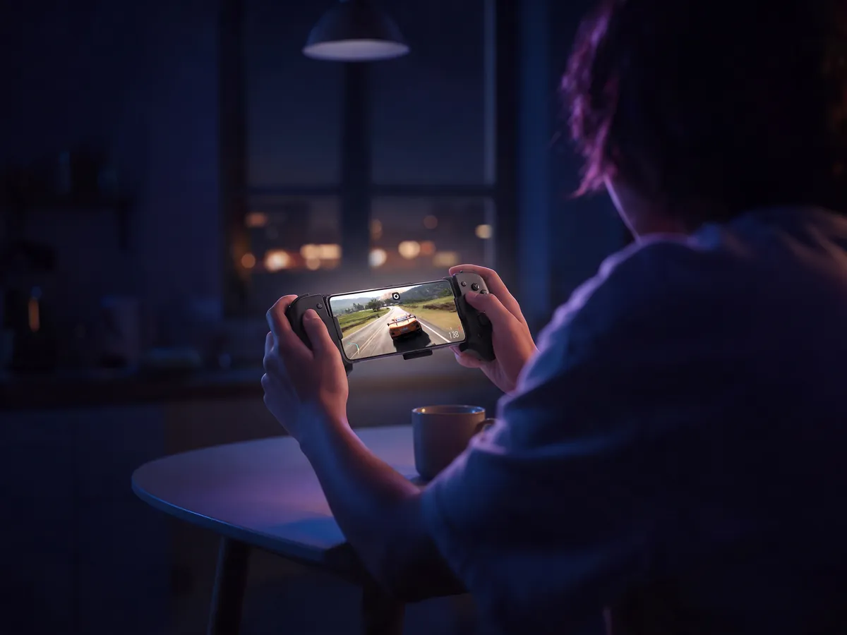 Forza Horizon 5 on an iPhone docked in a controller at a kitchen table
