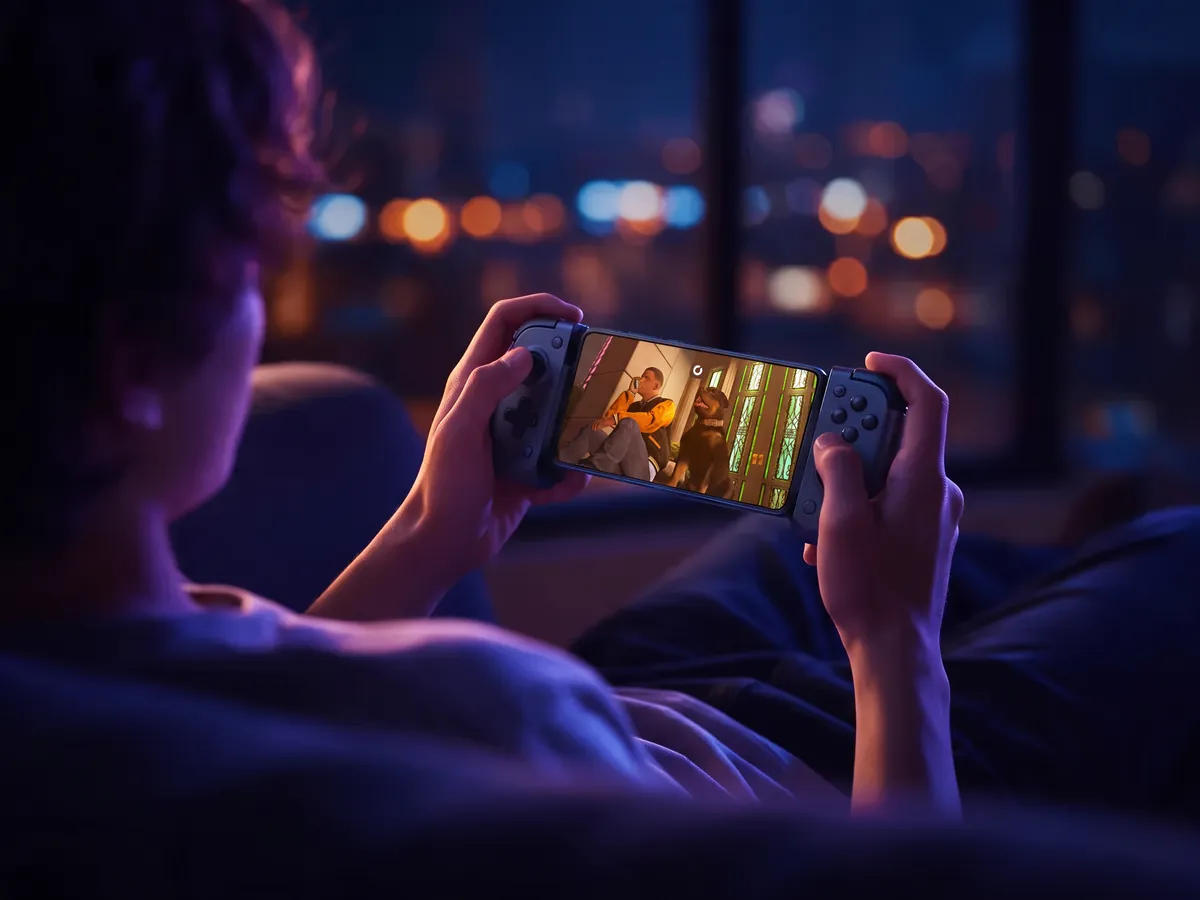 A player on a sofa playing GTA V on a phone docked in a controller